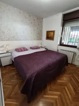 Spavaća soba sa bračnim krevetom, noćnim stočićima i parketom na podu. - image 36