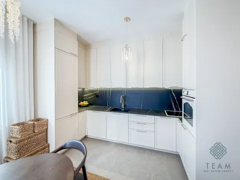 Modern white kitchen with black countertops and built-in appliances. - image 6