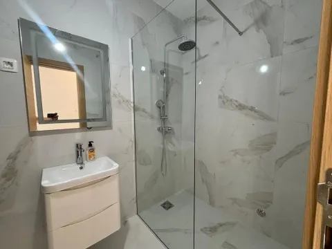 Modern bathroom with a sink, walk-in shower, and marble tiles. - image 9