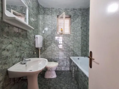 Bathroom tiled with ceramic tiles featuring a sink, toilet, and bathtub. - image 8