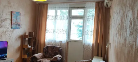 Living room with an armchair, TV, and balcony door. - image 4