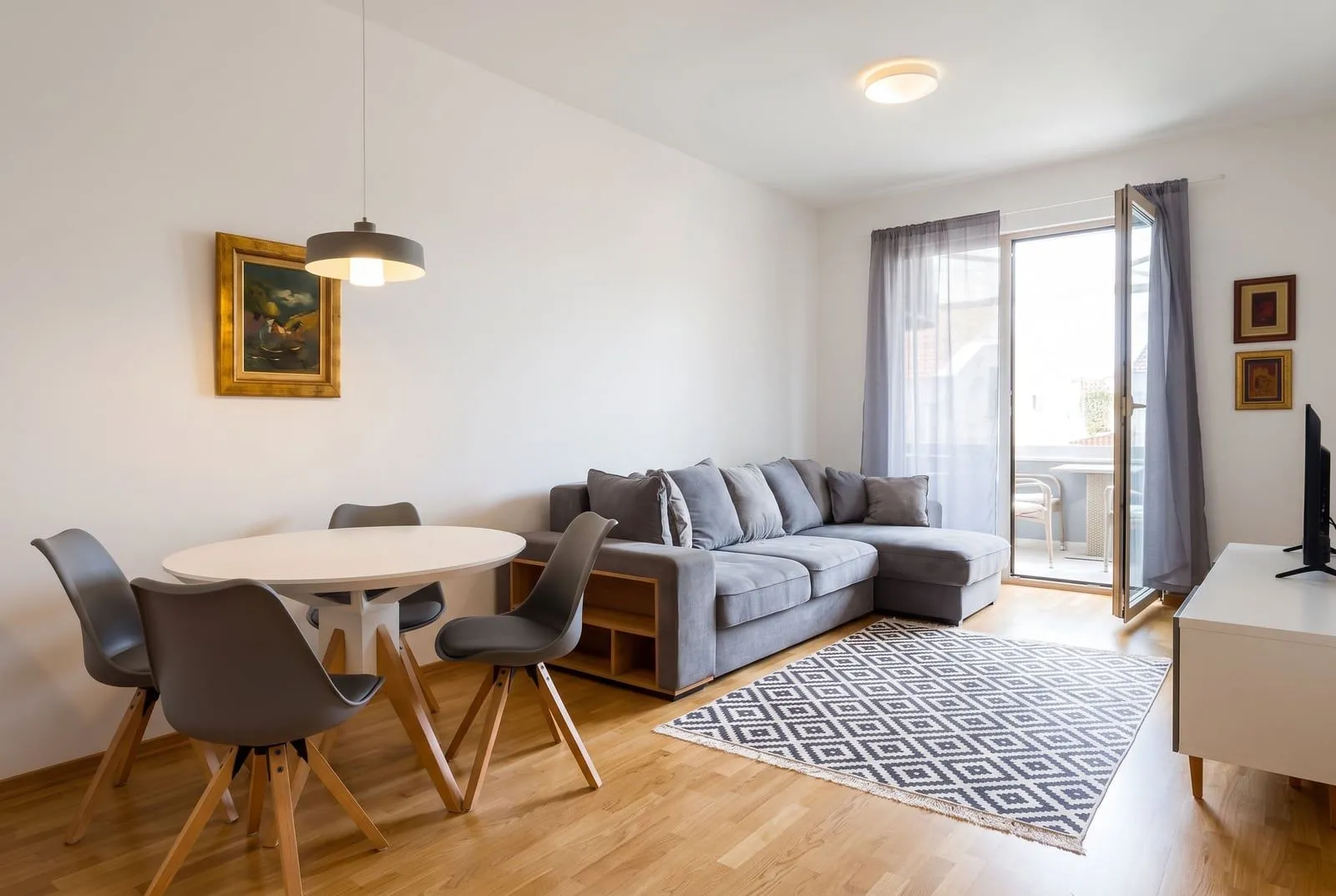 Bright living room with a sofa, dining table, and access to the terrace.