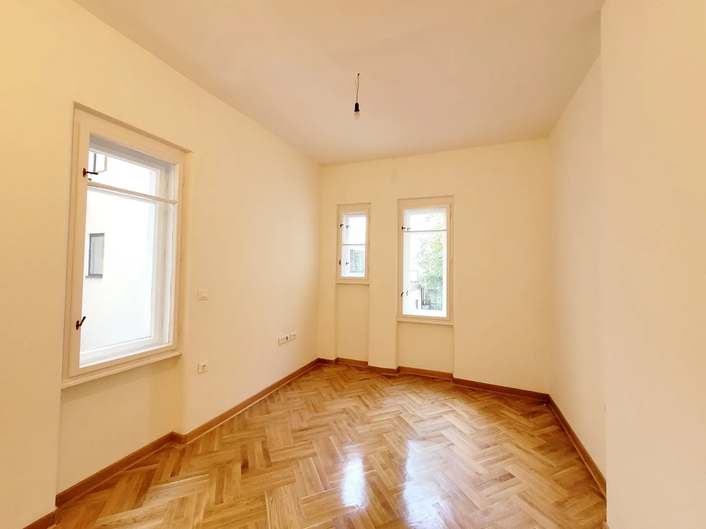 Empty room with light-colored walls and hardwood flooring.