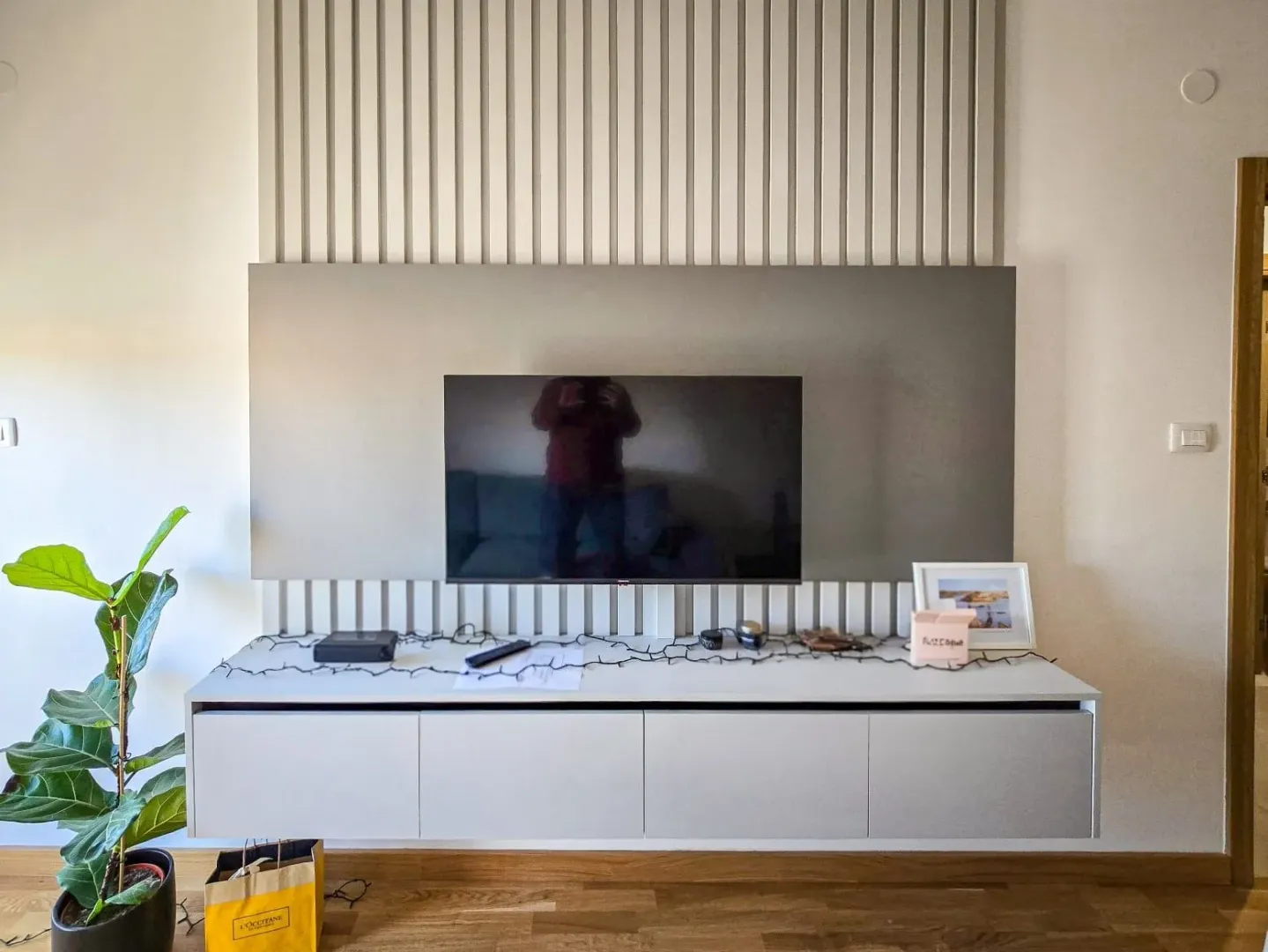 Moderan TV panel sa policom i drvenim letvicama na zidu.