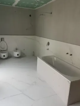 Bathroom under renovation with an installed bathtub, toilet bowl, and bidet. - image 6
