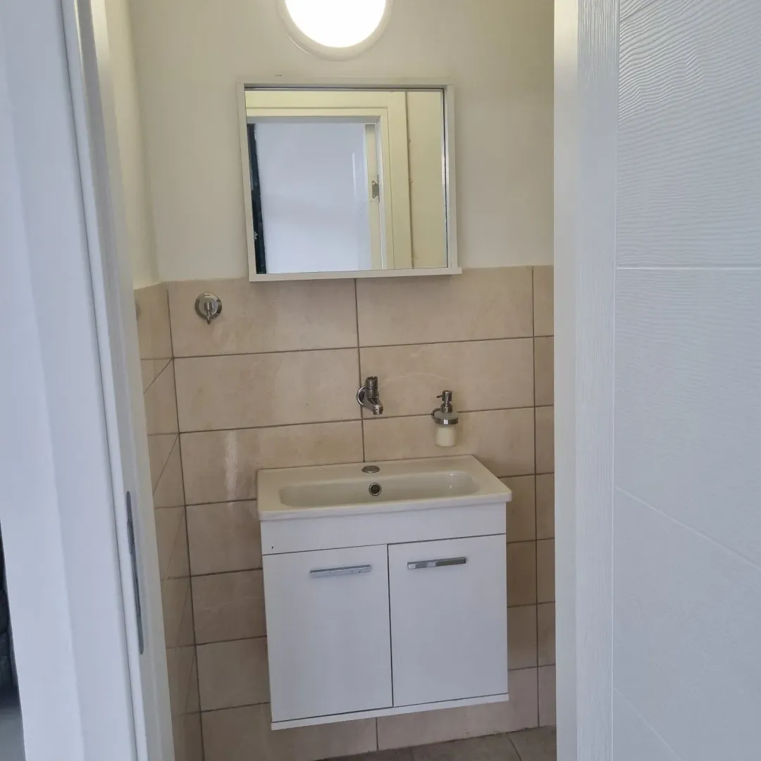A small bathroom featuring a white vanity and a mirror.