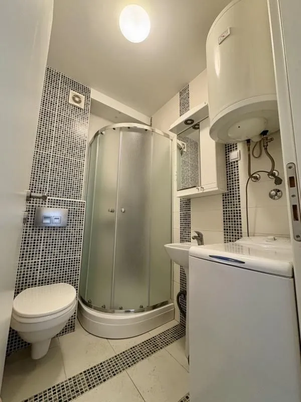 Manje kupatilo sa tuš kabinom, WC šoljom, umivaonikom i bojlerom.