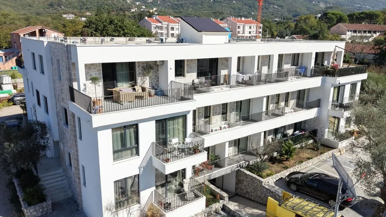 Side view of a modern multi-family residential building with balconies and parking.