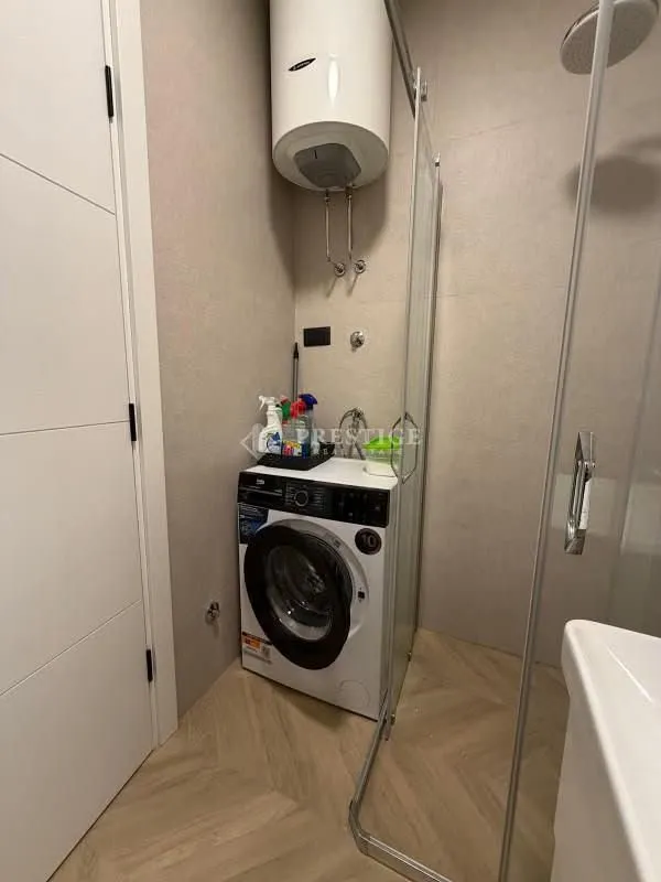 Smaller bathroom with a walk-in shower, washing machine, and water heater.