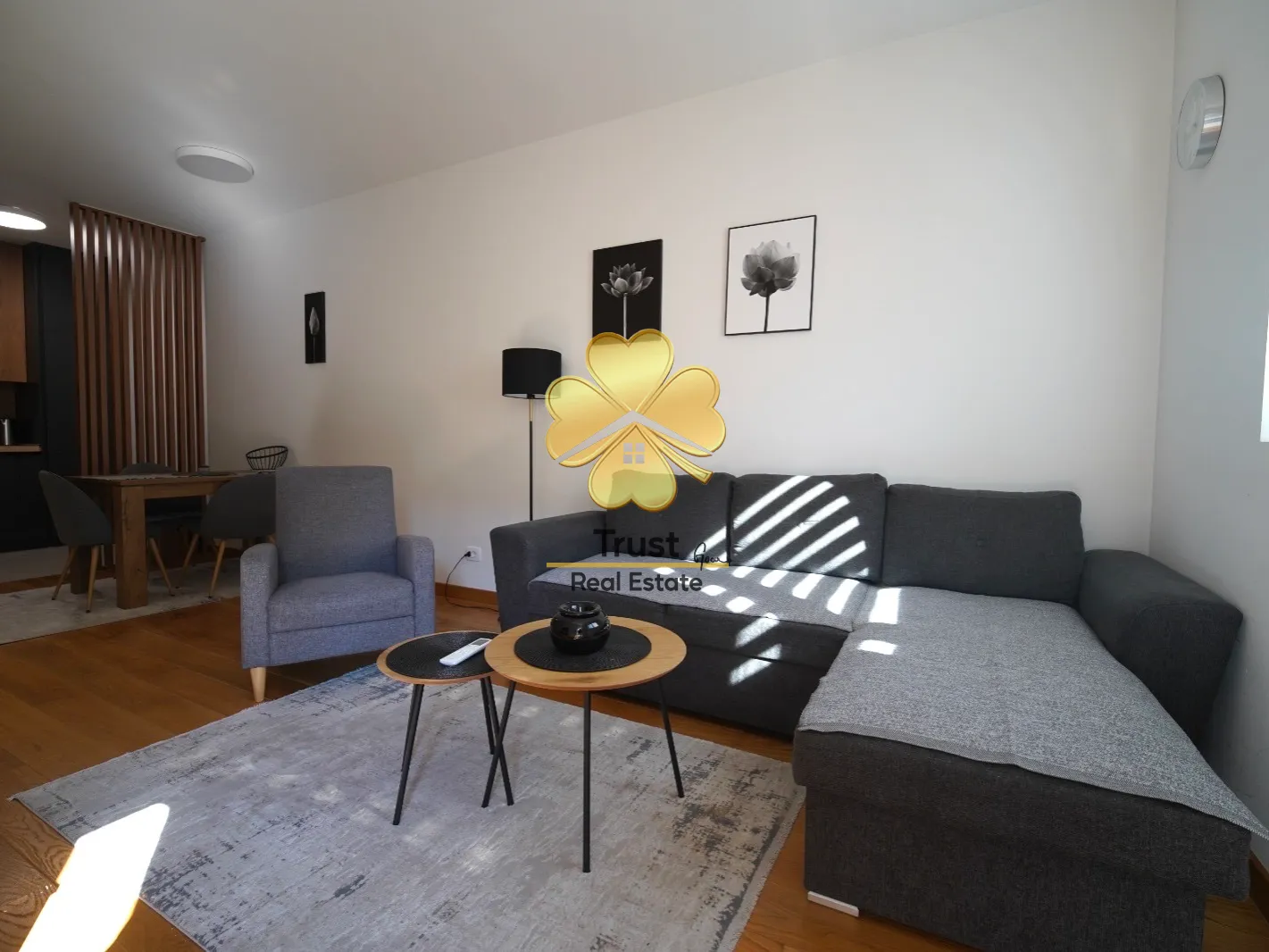 Living room with a sofa, coffee table, and dining area in the background.