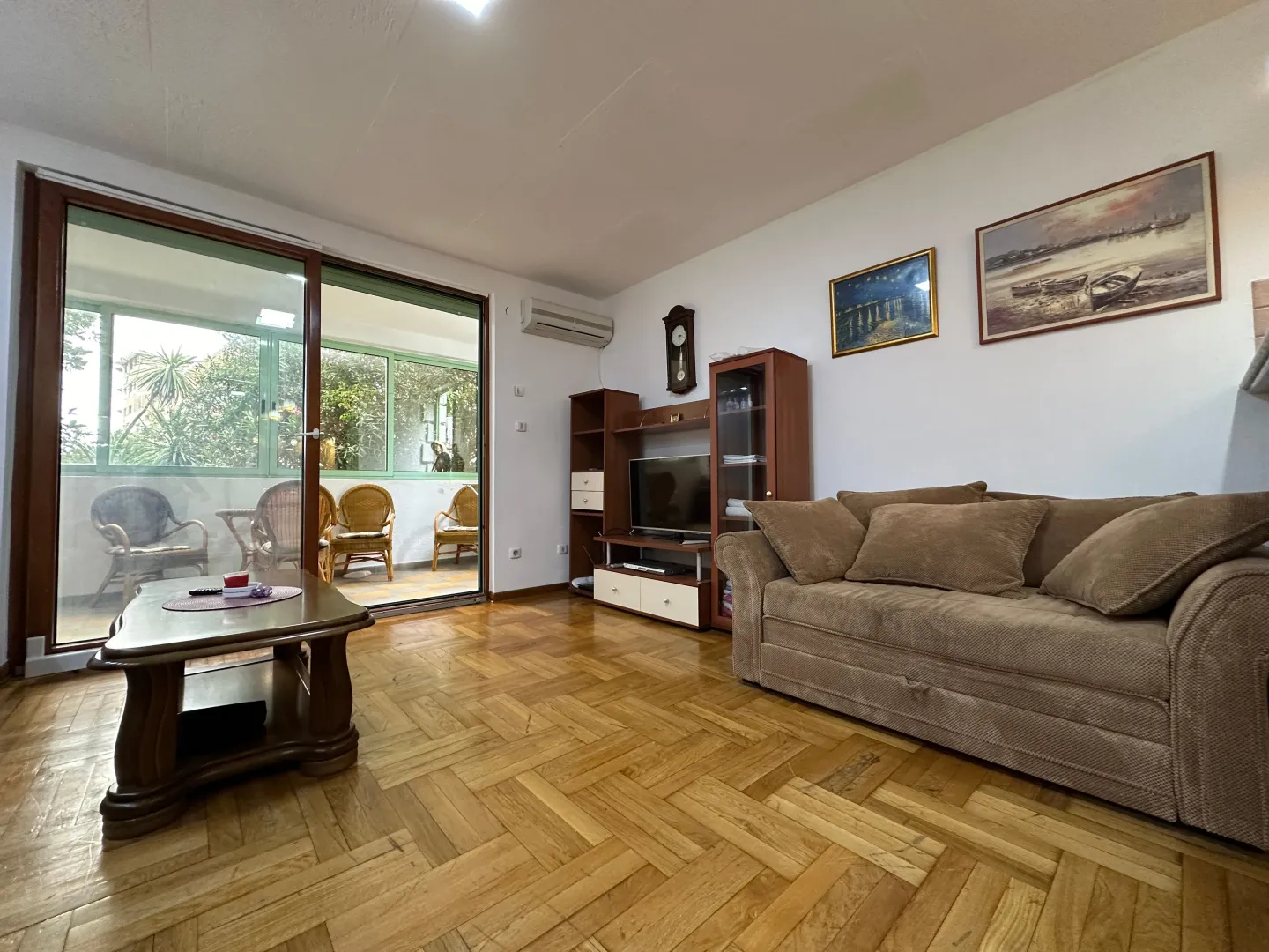 Living room with sofa set, wooden parquet flooring, and access to the terrace.