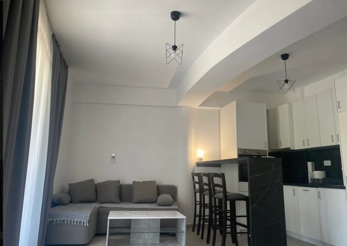 Dnevni boravak sa sjedećom garniturom i ugaonom kuhinjom.