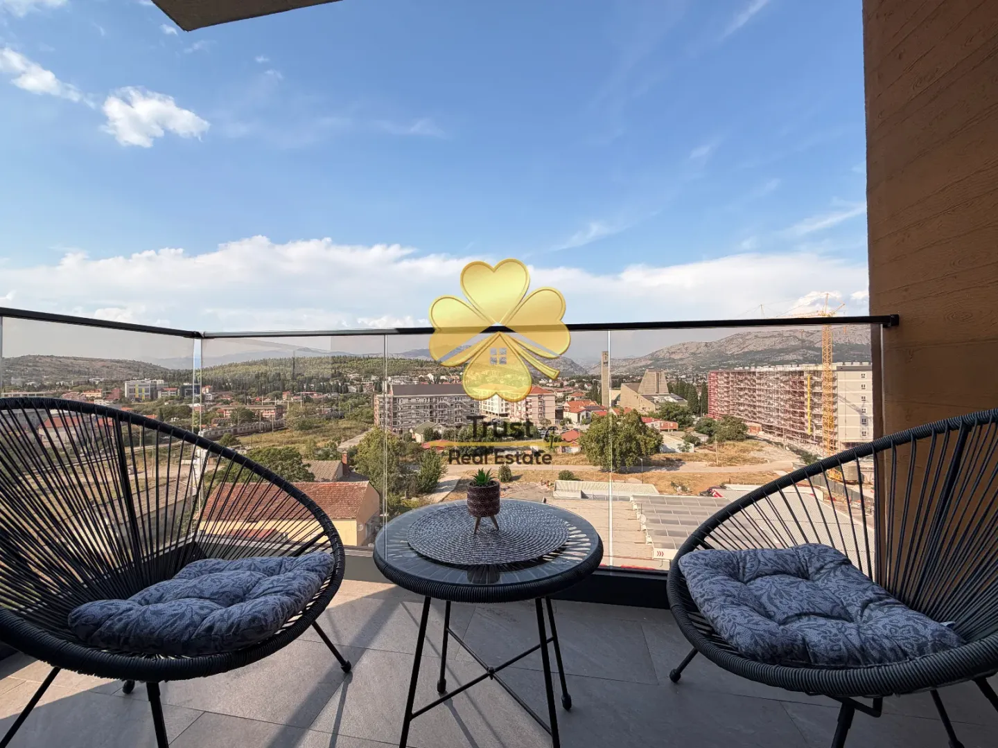Furnished terrace with a small table, two armchairs, and a city view.