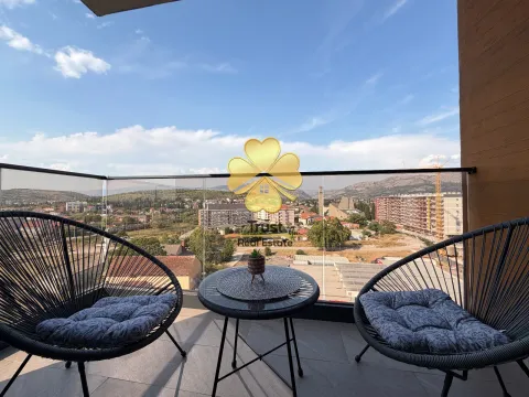 Furnished terrace with a small table, two armchairs, and a city view. - image 8
