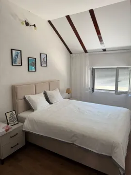 Bright bedroom with a double bed, white linens and a window. - image 2