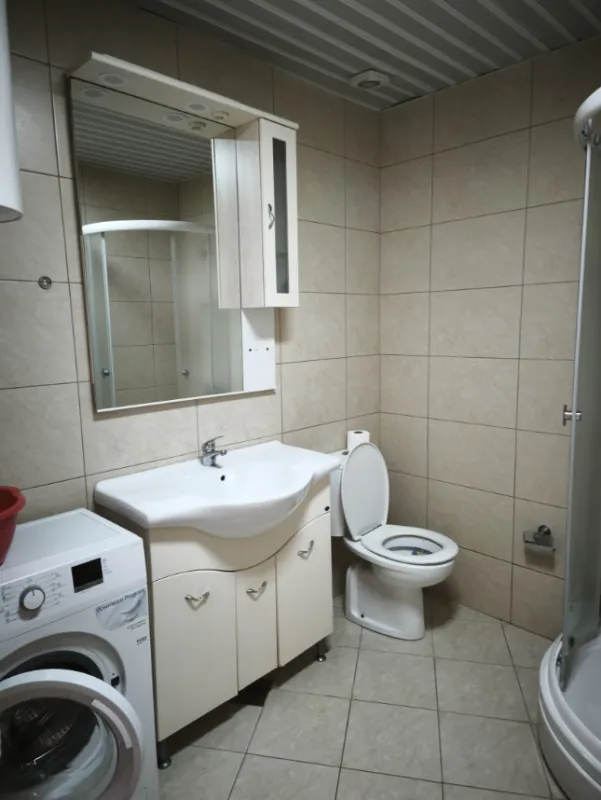 Kupatilo opremljeno umivaonikom, wc šoljom, tuš kabinom i mašinom za veš.