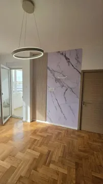 Prazna soba sa parketom, modernim lusterom i dekorativnim zidom. - image 9