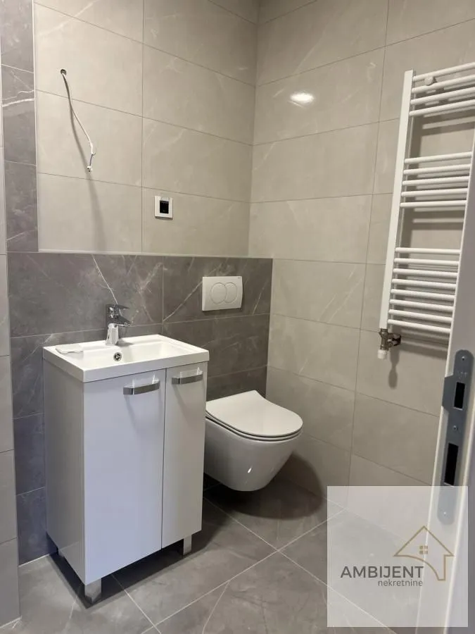 Manje kupatilo sa umivaonikom, WC šoljom i radijatorom za peškire.