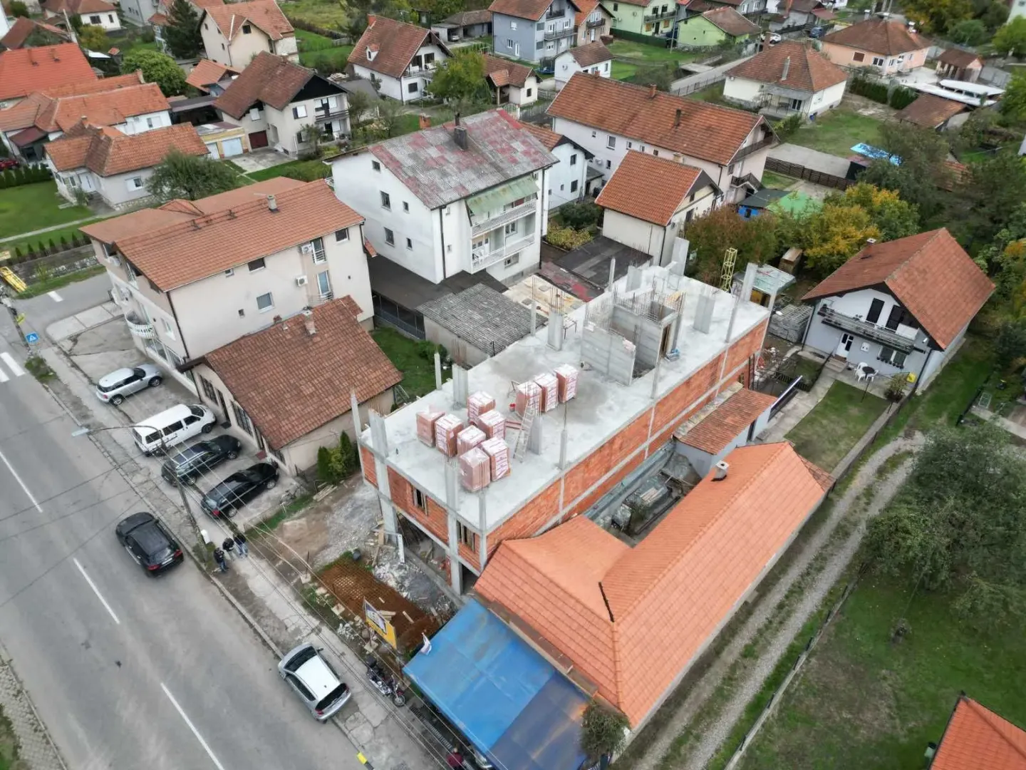 Pogled iz vazduha na kuću u izgradnji u naselju sa okolnim kućama i ulicom.