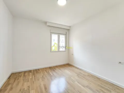 Empty room with white walls, wooden parquet flooring and a window. - image 4