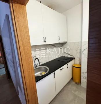 Manja bela kuhinja sa crnom radnom površinom i sudoperom. - image 5