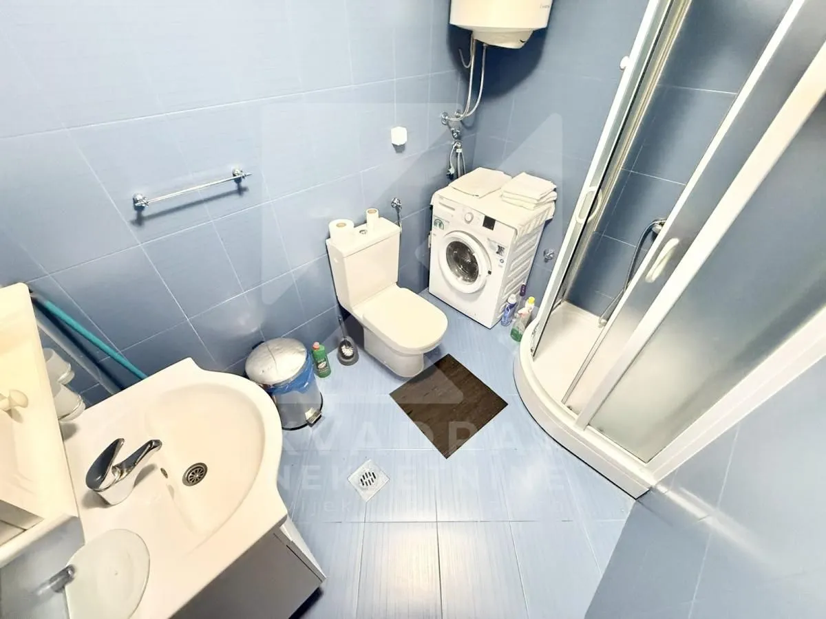 Bathroom equipped with a sink, toilet, shower cabin, and washing machine.