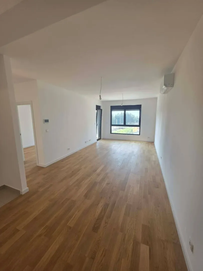 Empty bright room with wooden flooring and a window.