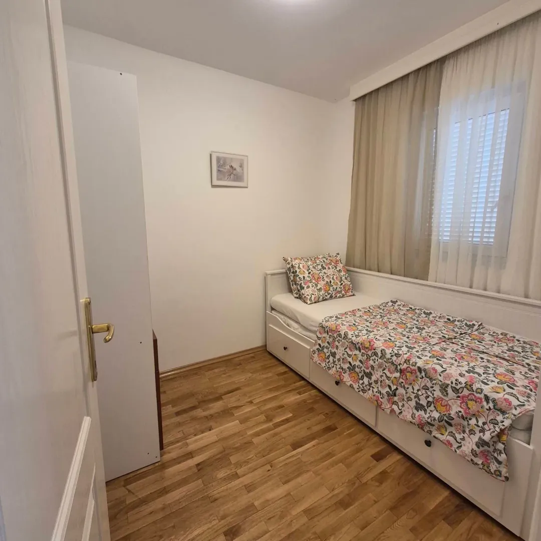 Small bedroom with a bed and wooden flooring.