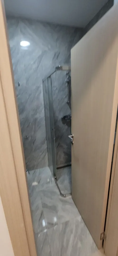 Pogled na kupatilo sa tuš kabinom kroz otvoren vrata.
