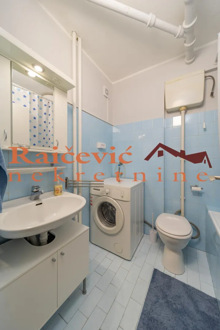 Bathroom with a washbasin, washing machine, and toilet.