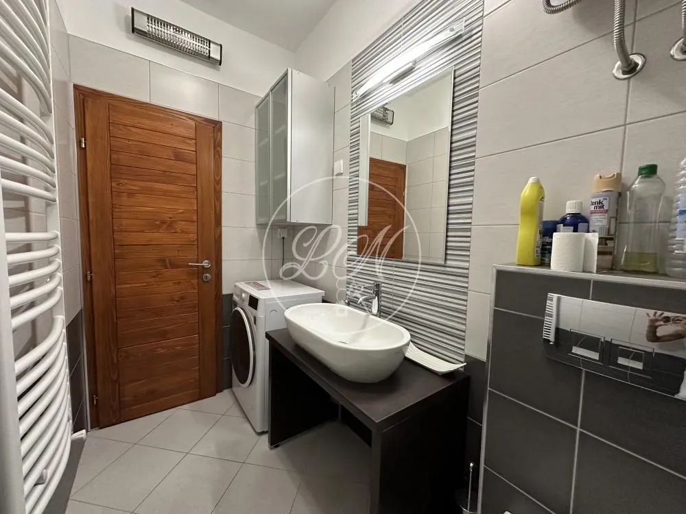 Modern bathroom with a washbasin, mirror, washing machine, and wooden door.