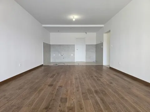 Empty room with laminate flooring and a designated kitchen area. - image 2