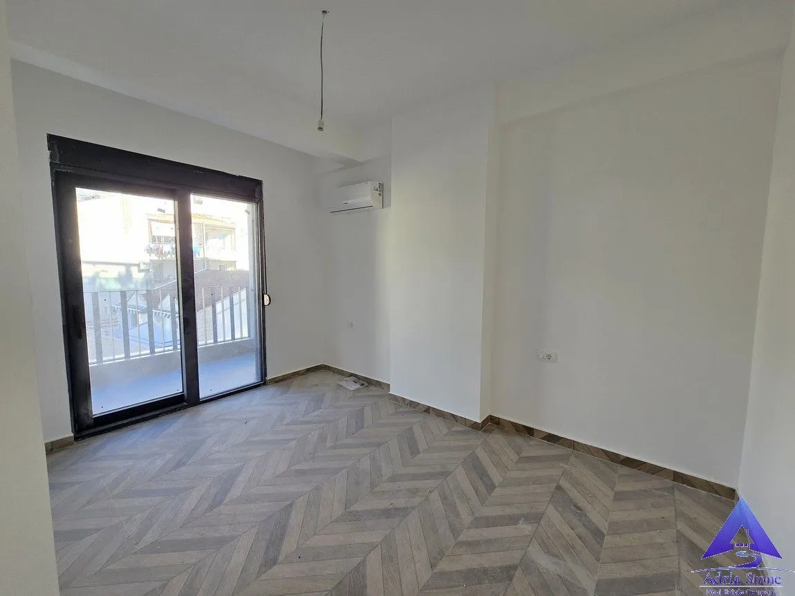 Empty room with herringbone laminate flooring and access to the terrace.
