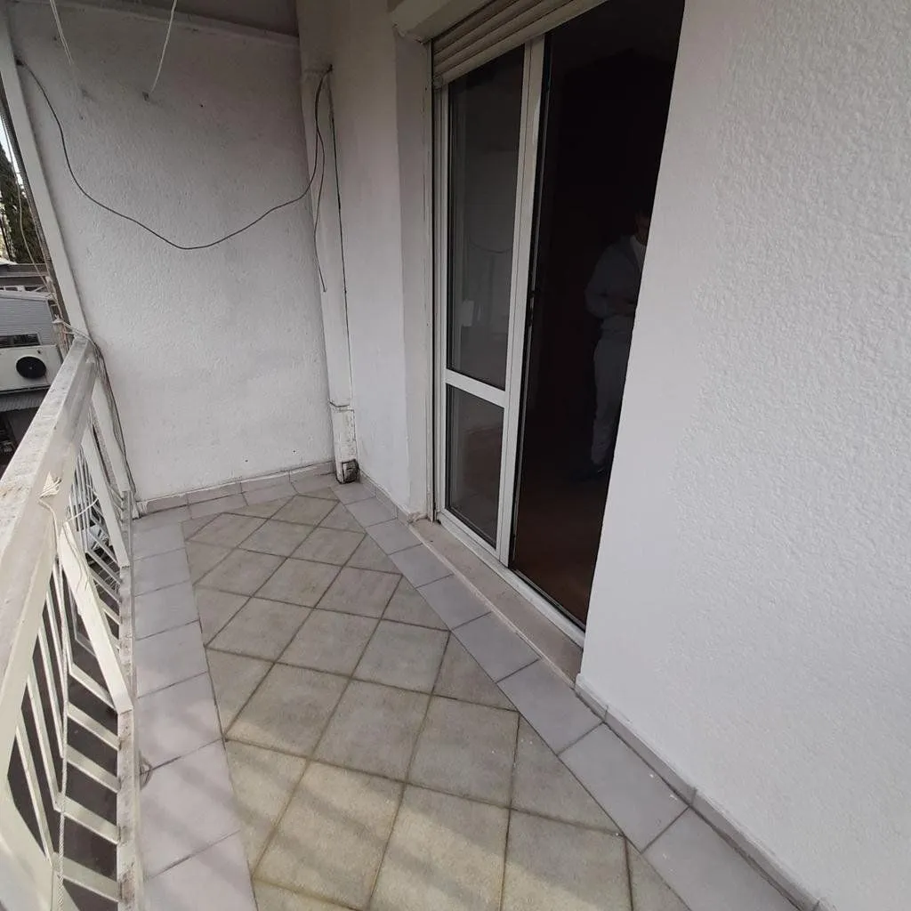 Nenamešten balkon sa keramičkim pločicama i izlazom u prostoriju.