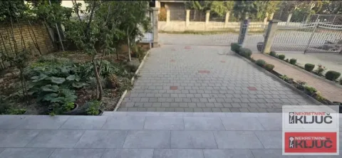 Paved courtyard and driveway in front of the house with a landscaped garden and fence. - image 2