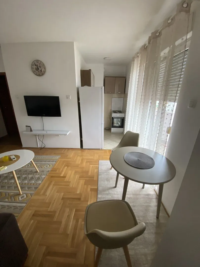 Svijetla dnevna soba sa trpezarijskim stolom i kuhinjom u pozadini.