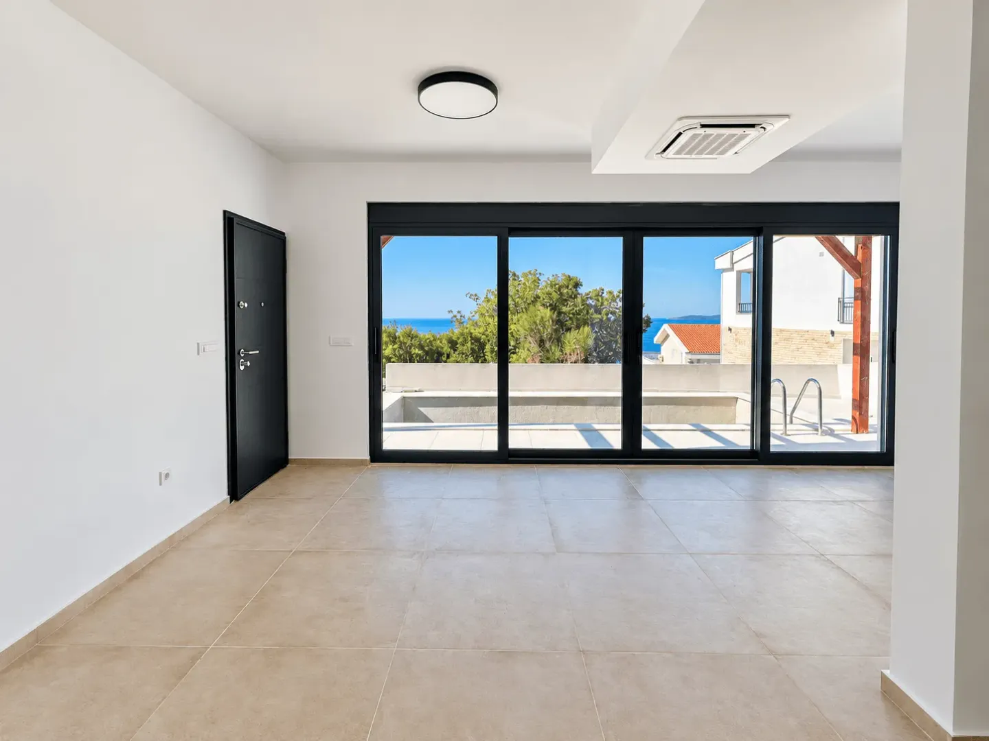 Empty bright room with large glass sliding doors and a sea view.