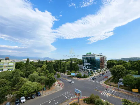 View from the apartment overlooking a city intersection and green areas. - image 7