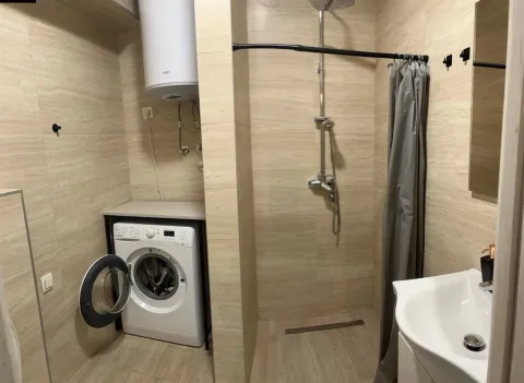 Smaller bathroom with a walk-in shower, washbasin, and washing machine. - image 11