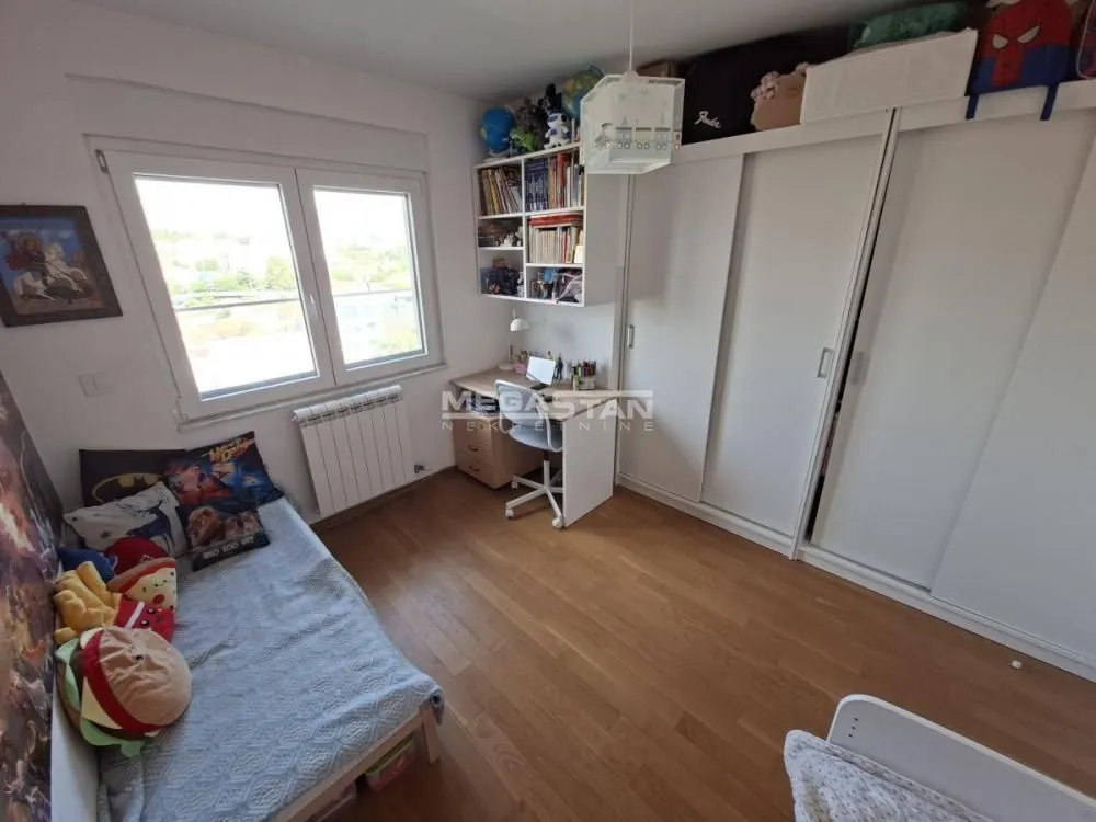 Children's bedroom with a bed, desk, large wardrobe, and window.