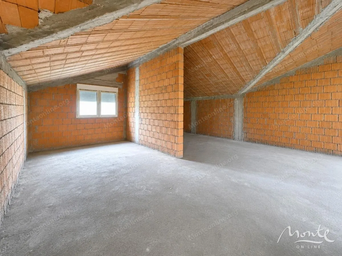 Neuređena potkrovna prostorija u grubim radovima sa opekom i betonskim podom.