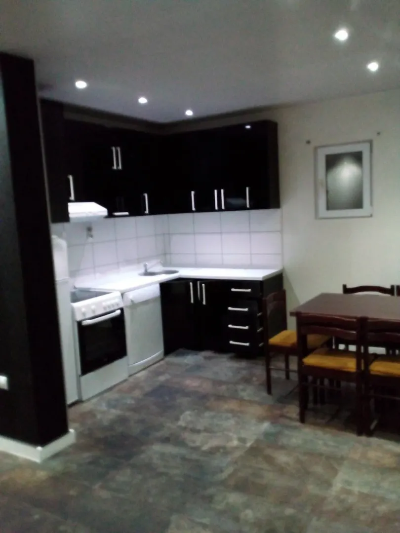 A kitchen with dark cabinets and a dining table with chairs.