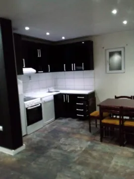 A kitchen with dark cabinets and a dining table with chairs. - image 4