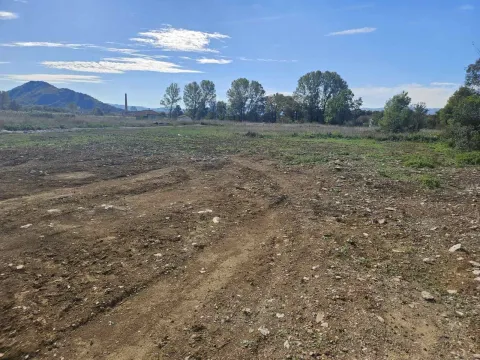 Prostran i ravan građevinski plac okružen drvećem pod vedrim nebom. - image 4