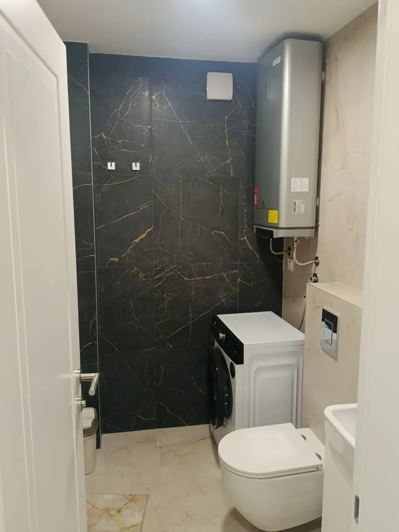 Modernly equipped bathroom with a washing machine and a built-in water heater.