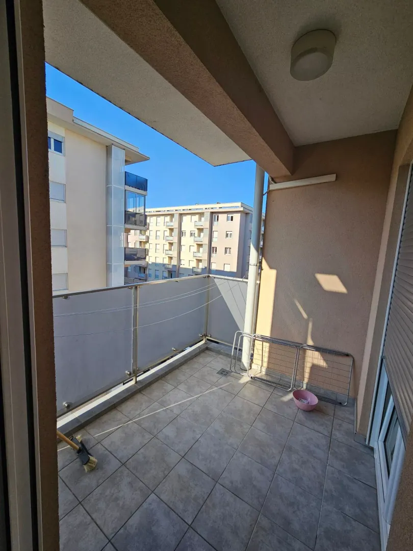 Covered balcony with ceramic tiles and a view of surrounding buildings.