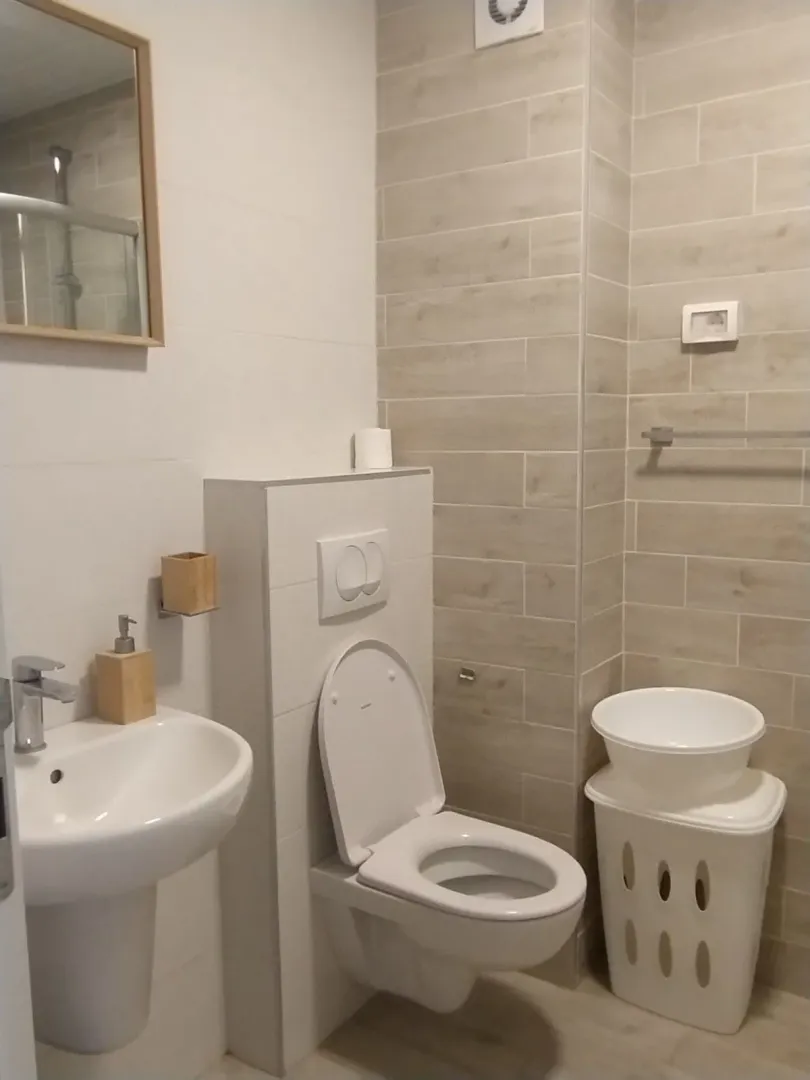 Simple bathroom with light tiles, a sink, and a toilet.