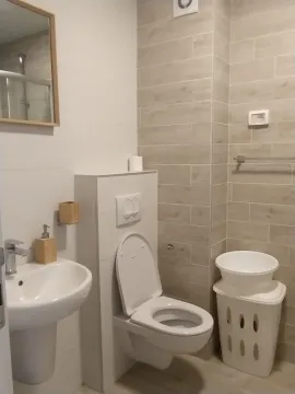 Simple bathroom with light tiles, a sink, and a toilet. - image 7
