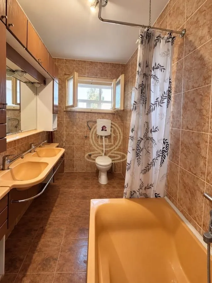 Tiled bathroom featuring a bathtub, double vanity sink, and a window.