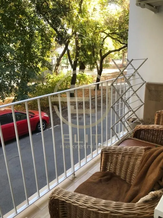 Manji namešten balkon sa pogledom na ulicu i drveće.
